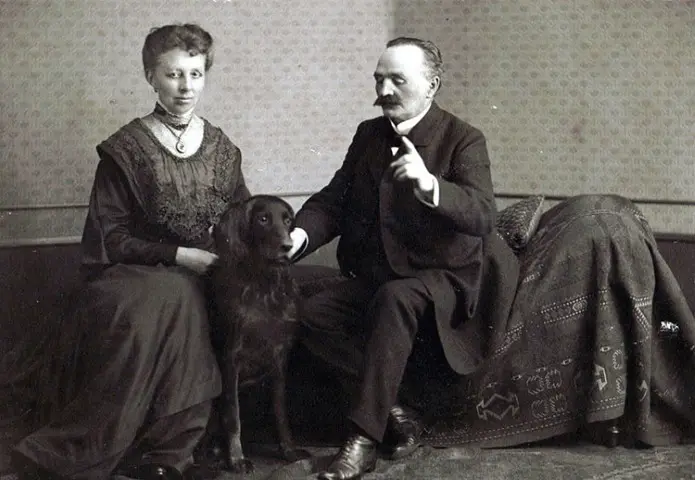 Das historische Schwarz-Weiß-Foto zeigt ein Ehepaar in zeittypischer Kleidung, sitzend mit einem Hund zwischen ihnen. Die Aufnahme dokumentiert die frühe Geschichte von Hof Bimöhlen und vermittelt einen Eindruck vom ländlichen Leben vergangener Generationen.
